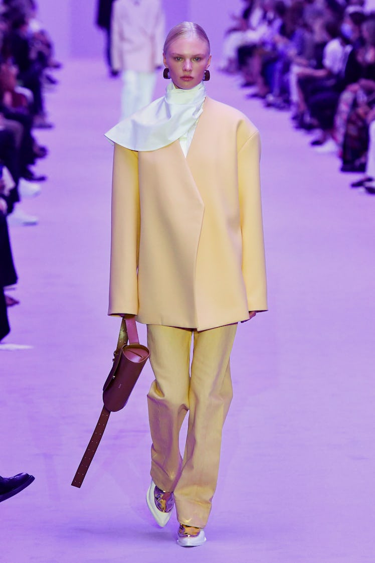 A model walking the Jil Sander show at Milan Fashion Week Spring 2022 in an oversized yellow suit