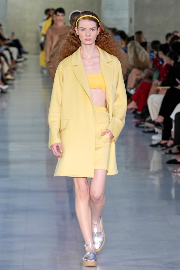 A model walking the Max Mara fashion show at Milan Fashion Week Spring 2022 in a long yellow blazer ...