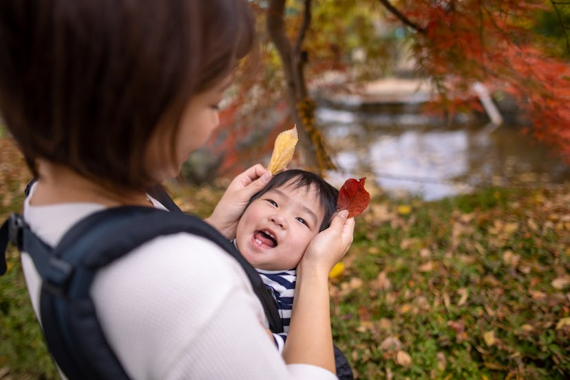 mom with baby in carrier during autumn in park in a round up of scorpio boy names