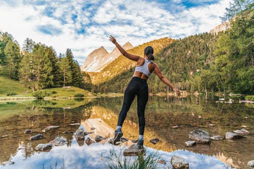 A woman balances on a rock in a river. These are the most brave of all zodiac signs, according to as...