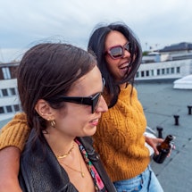 Two young latinx women drink on a rooftop. Here's what latinx means to them, and how they explain th...
