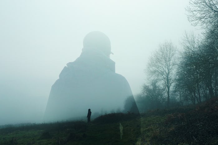 A double exposure of an atmospheric half transparent man looking at a person standing on the edge of...