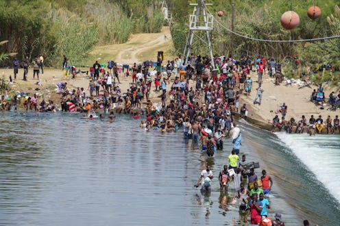 Migrants, many of them Haitian, cross the Rio Grande to get food and supplies near the Del Rio-Acuna...