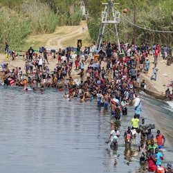 Migrants, many of them Haitian, cross the Rio Grande to get food and supplies near the Del Rio-Acuna...