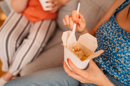 Woman eating her ordered lunch at home with friend. Eating pasta. Close up.