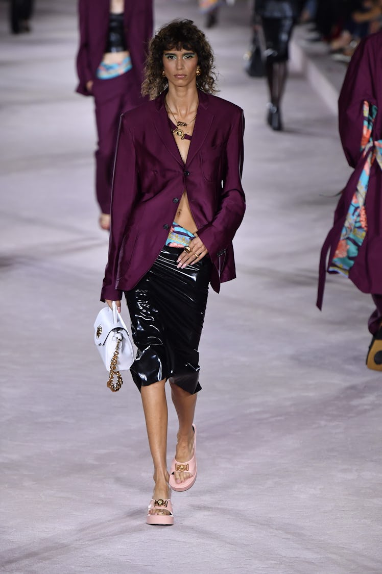 A model on the runway of Versace Ready to Wear Spring/Summer 2022 in a purple blazer and low-rise sh...