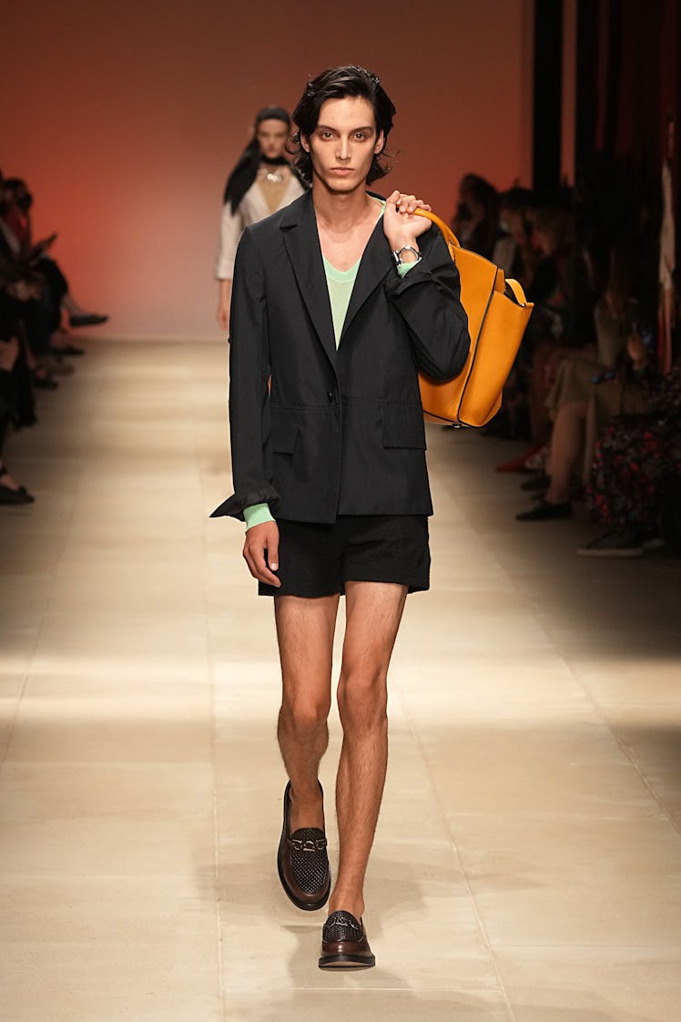 A model walking the runway at the Salvatore Ferragamo show in black shorts, a matching blazer and lo...