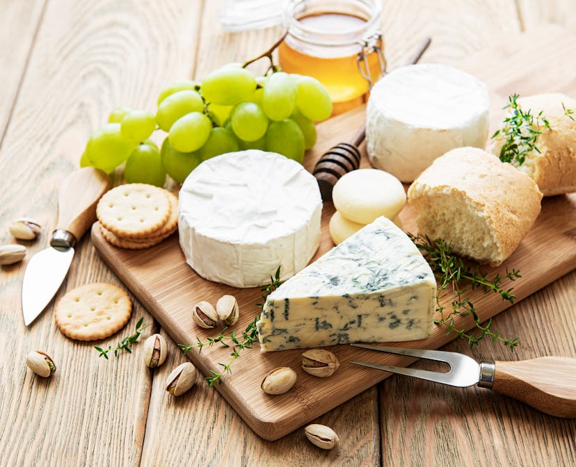 Cheese selection, honey and grape on old wooden background