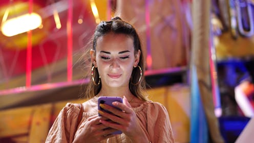 Woman using smart phone in amusement park.