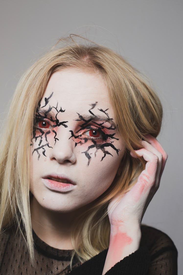 A young blonde woman with creepy, cracked Halloween eye makeup