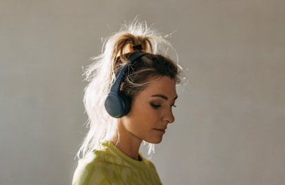 Close up photo of a young female with headphones in sportswear preparing for a warm up exercise in g...