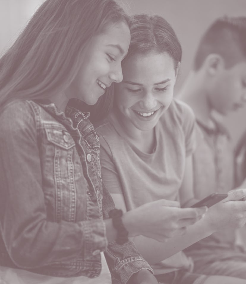 A group of multi-ethnic high school students sit together in a row. They are each dressed casually ...