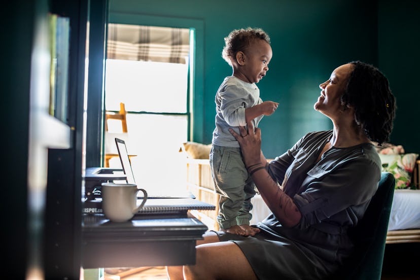 Woman working from home while holding baby
