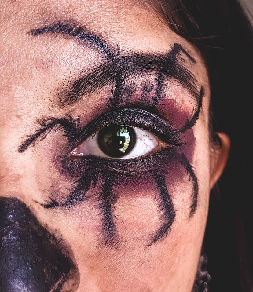 A young woman with a spider Halloween eye makeup look