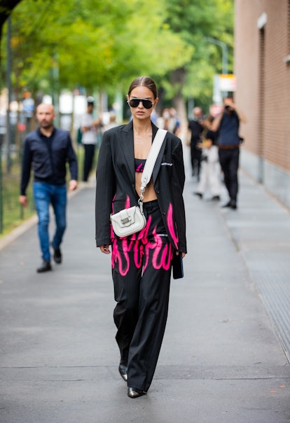 MILAN, ITALY - SEPTEMBER 22: A guest is seen wearing Dior bag, pants and blazer with fire flame prin...