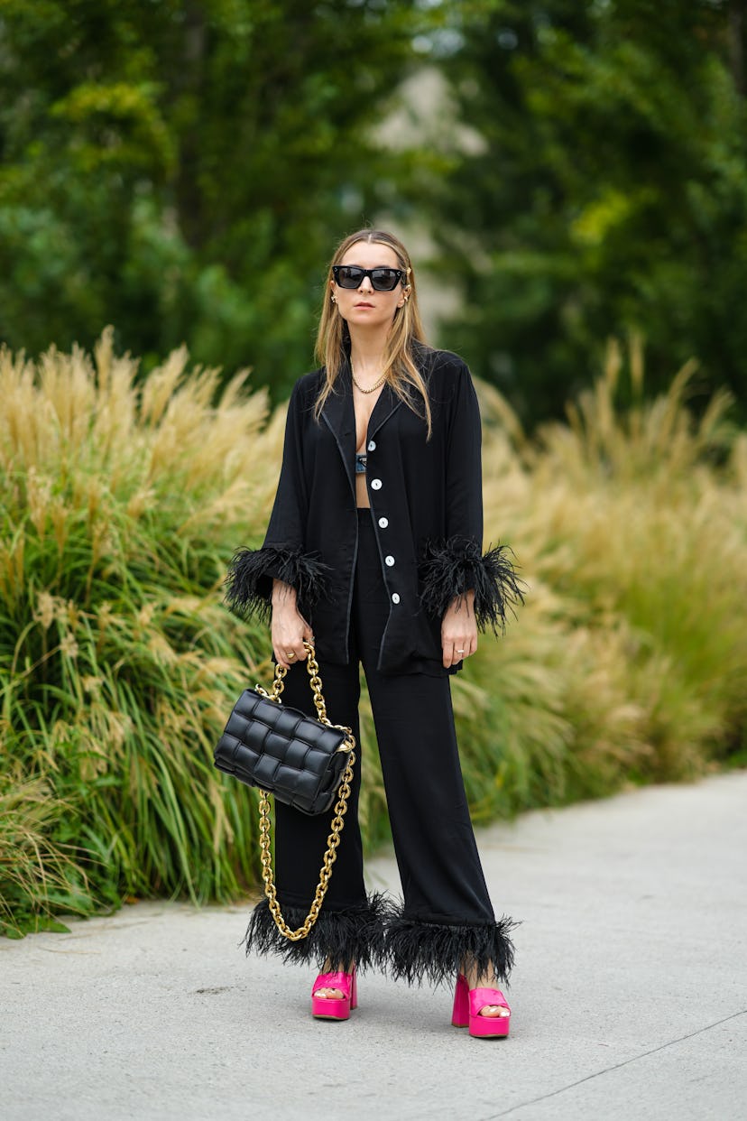 MILAN, ITALY - SEPTEMBER 25: Julia Comil wears black sunglasses, gold and pearls earrings, a gold ch...