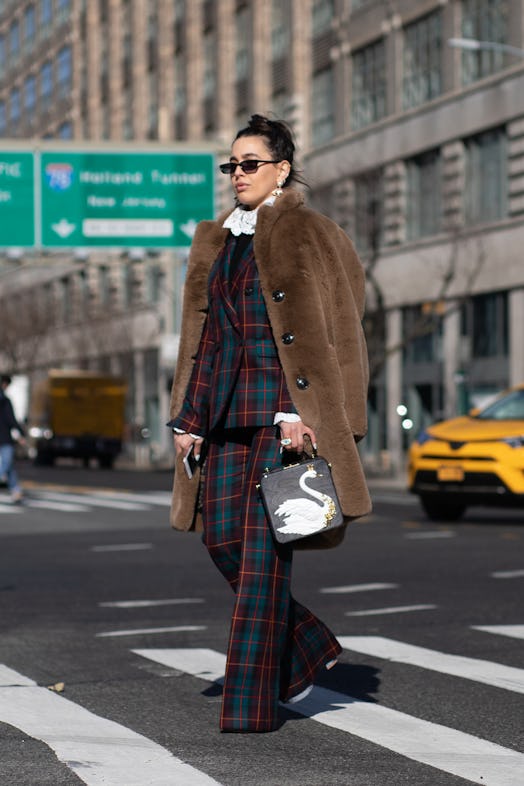 A guest is seen on the street wearing brown fur coat with navy/merlot/dark green plaid outfit on Feb...