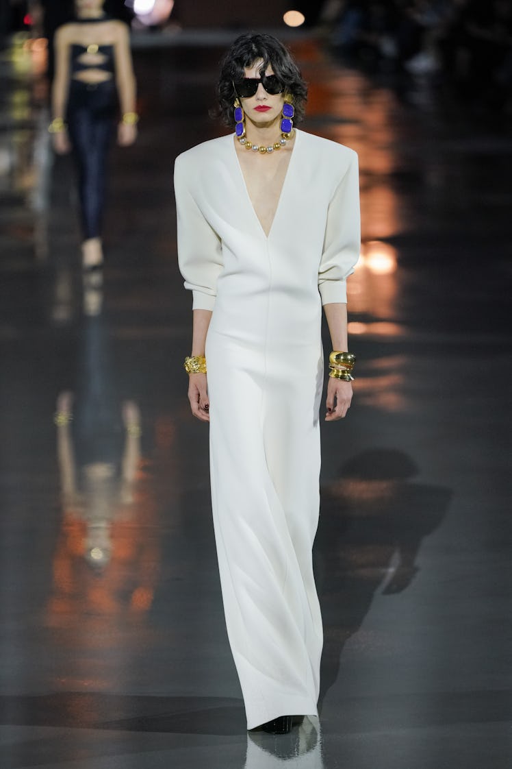 A model walking in a white Saint Laurent dress on the runway