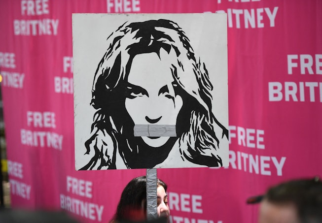 A woman holds a poster of Britney with her mouth taped shut as fans and supporters gather outside th...