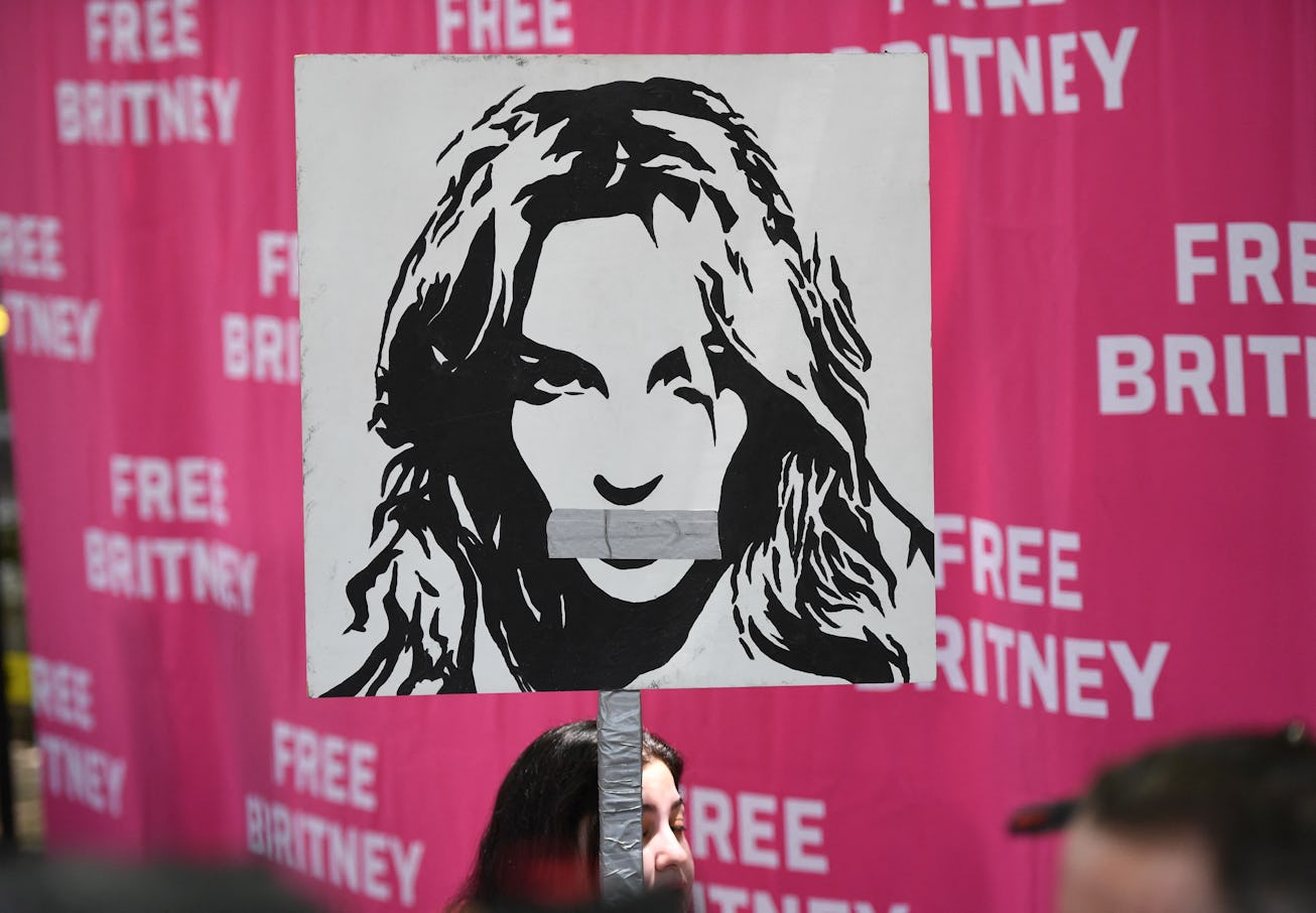 A woman holds a poster of Britney with her mouth taped shut as fans and supporters gather outside th...