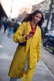 MILAN, ITALY - FEBRUARY 22: Model Jordan Daniels checks her phon and wears a yellow jacket after the...
