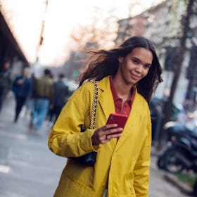 MILAN, ITALY - FEBRUARY 22: Model Jordan Daniels checks her phon and wears a yellow jacket after the...