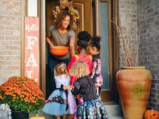 A diverse group of children, dressed in costumes, trick or treating in a residential USA neighborhoo...