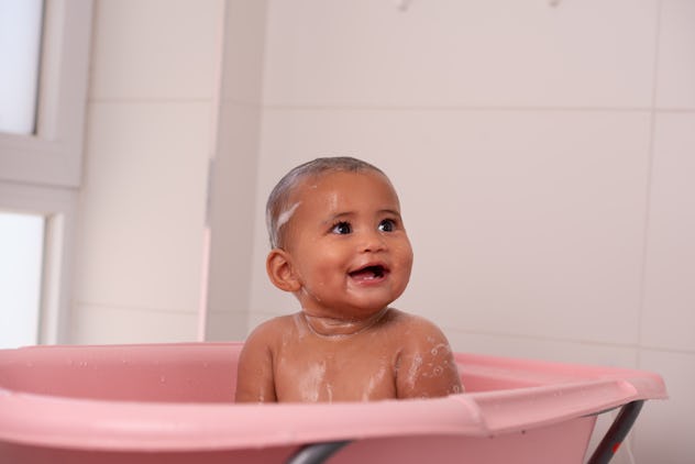 A cute baby is bathing in the tub.