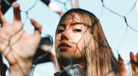 woman looking through fence with serious expression as she reflects on emotional meaning of october ...