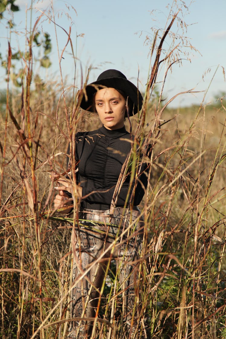woman staring into camera as she stands out in a field, reflecting on scorpio season 2021 will be th...