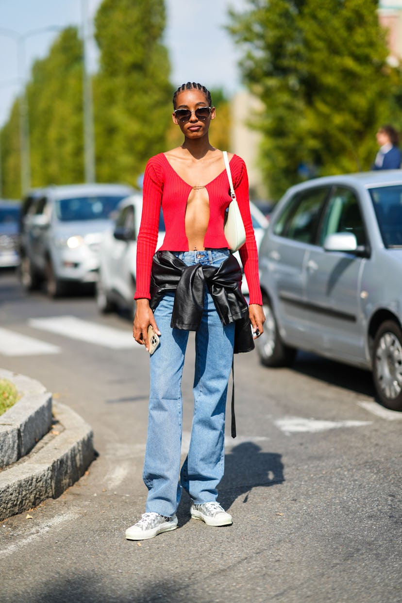 MILAN, ITALY - SEPTEMBER 23: A guest wears sunglasses, a red ribbed cropped long sleeves open pullov...