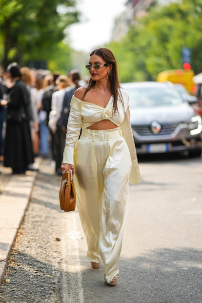 MILAN, ITALY - SEPTEMBER 22: Karen Wazen Bakhazi wears black and gold sunglasses, gold peandant earr...