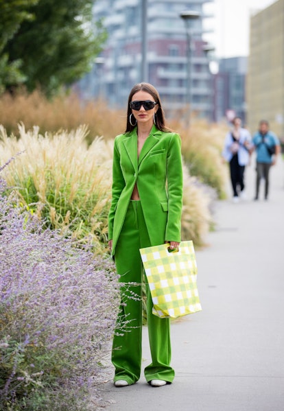 MILAN, ITALY - SEPTEMBER 25: A guest is seen wearing green suit, checkered bag outside MSGM during t...