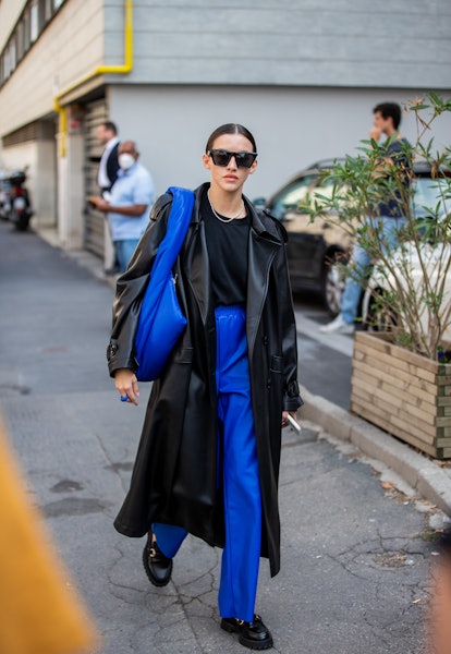 MILAN, ITALY - SEPTEMBER 23: A guest is seen wearing black coat, blue pants, bag outside Etro during...