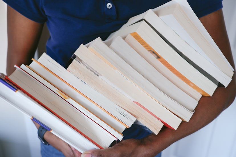 Close-up of unrecognizable black woman carrying a heap of books