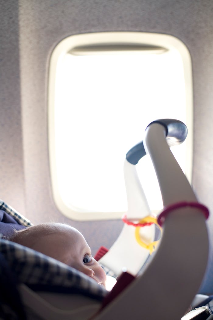 A baby boy sits in a car seat during an airplane flight. (Photo by James Leynse/Corbis via Getty Ima...