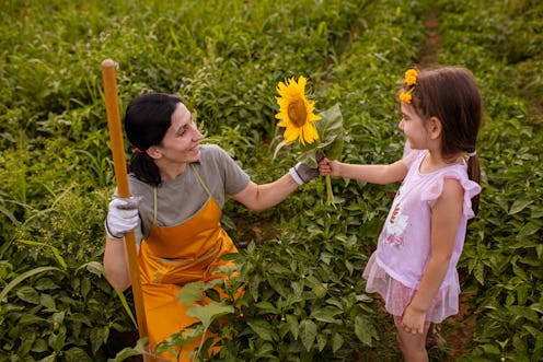 Adorable and caring daughter, visiting her mother on their organic farm/agricultural field, to see i...