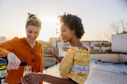 Smiling young women pour a glass of champagne. These are the traits of libra-scorpio cusp signs.