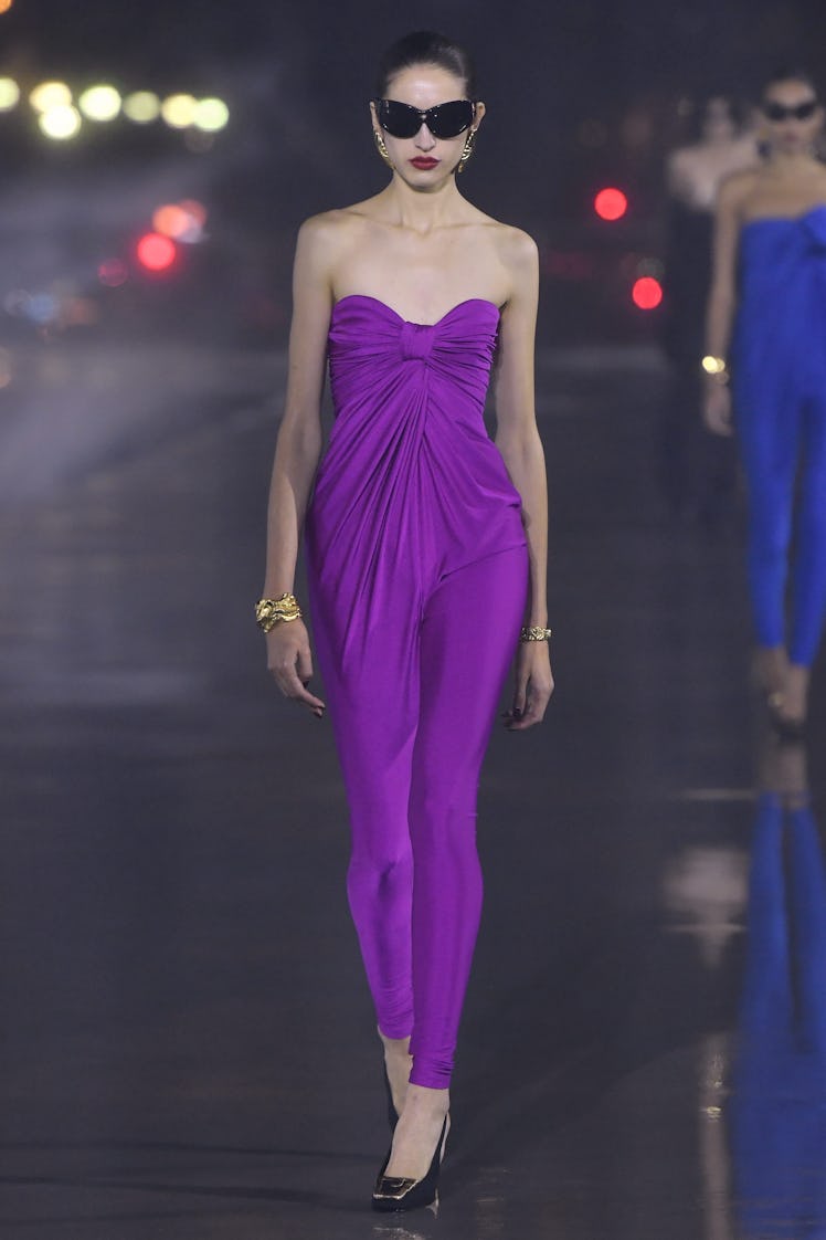 A model walking in a purple Saint Laurent dress on the runway