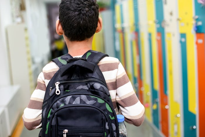 Unrecognizable boy in a school hallway. About 9-10 years old, mixed race male.