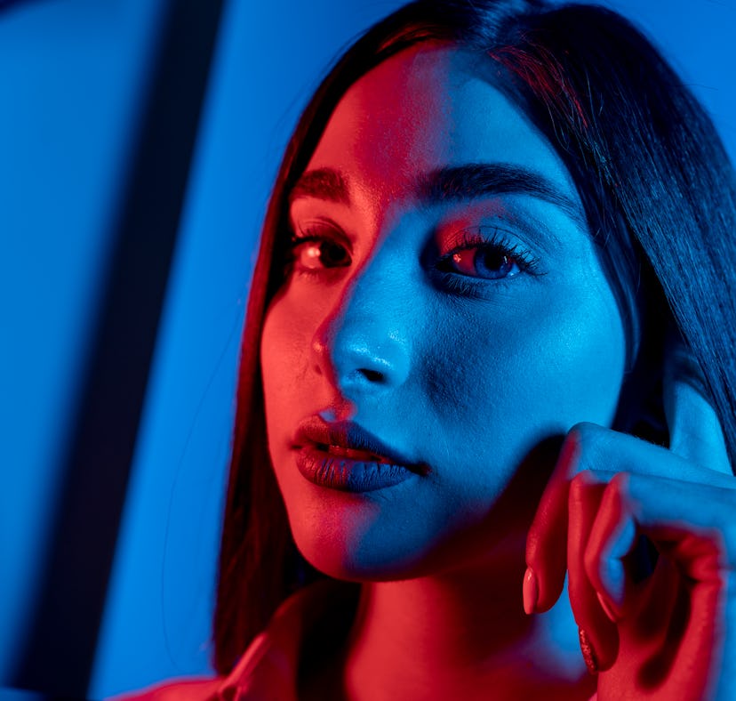 High Fashion model woman in colorful bright neon blue and purple lights posing in studio. Portrait o...