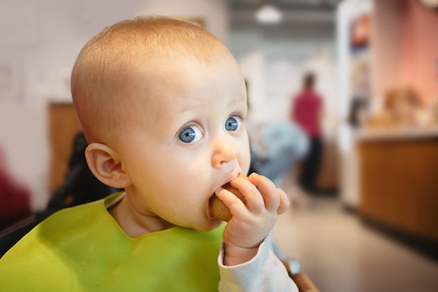 Cute 9 month old baby girl enjoying a snack on her first visit to a cafe