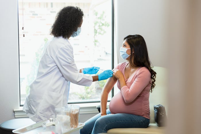 The unrecognizable mature adult technician and the mid adult pregnant woman both wear protective gea...