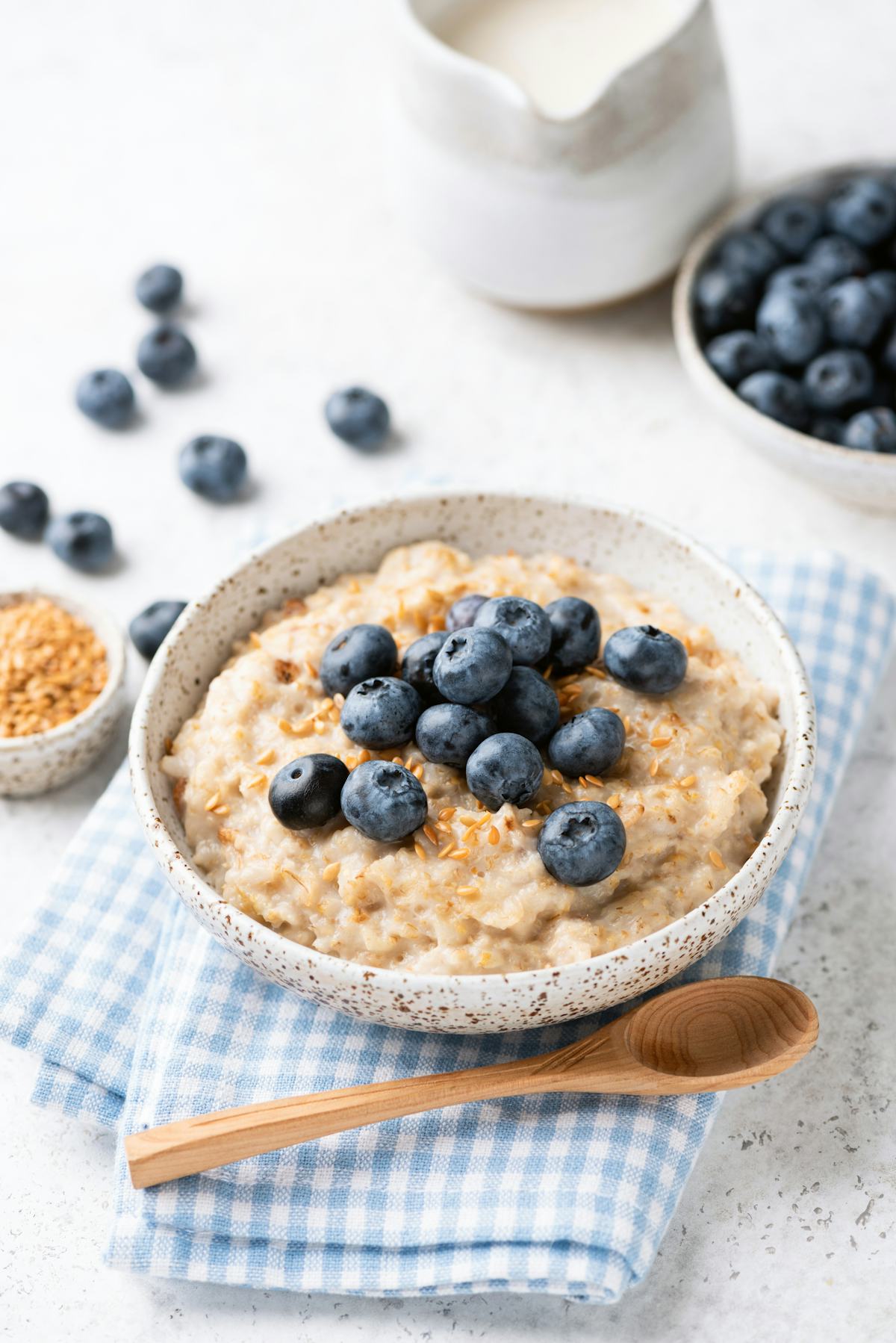Oatmeal bowl with blueberries and flax seeds on blue textile. Healthy breakfast meal
