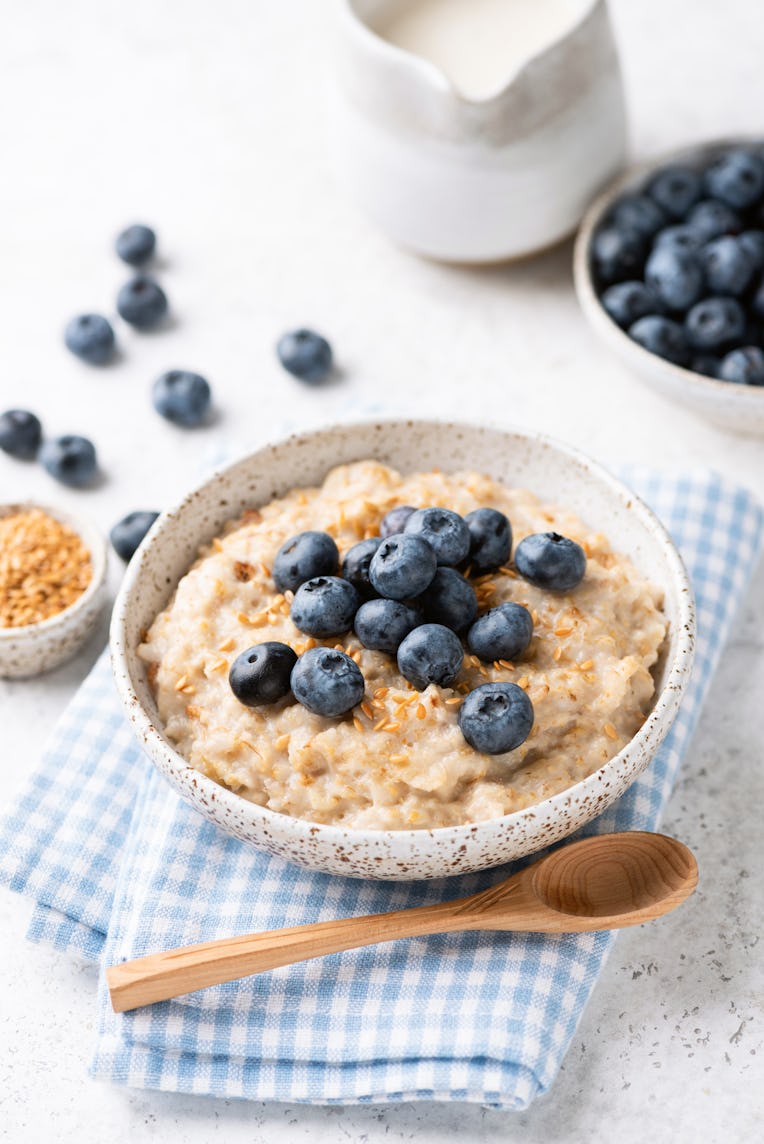 Oatmeal bowl with blueberries and flax seeds on blue textile. Healthy breakfast meal