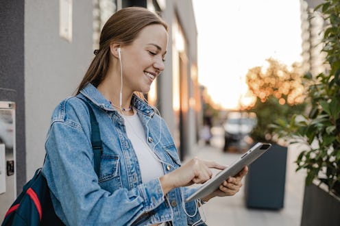 Young blond hair woman on the street holding a digital tablet and walking