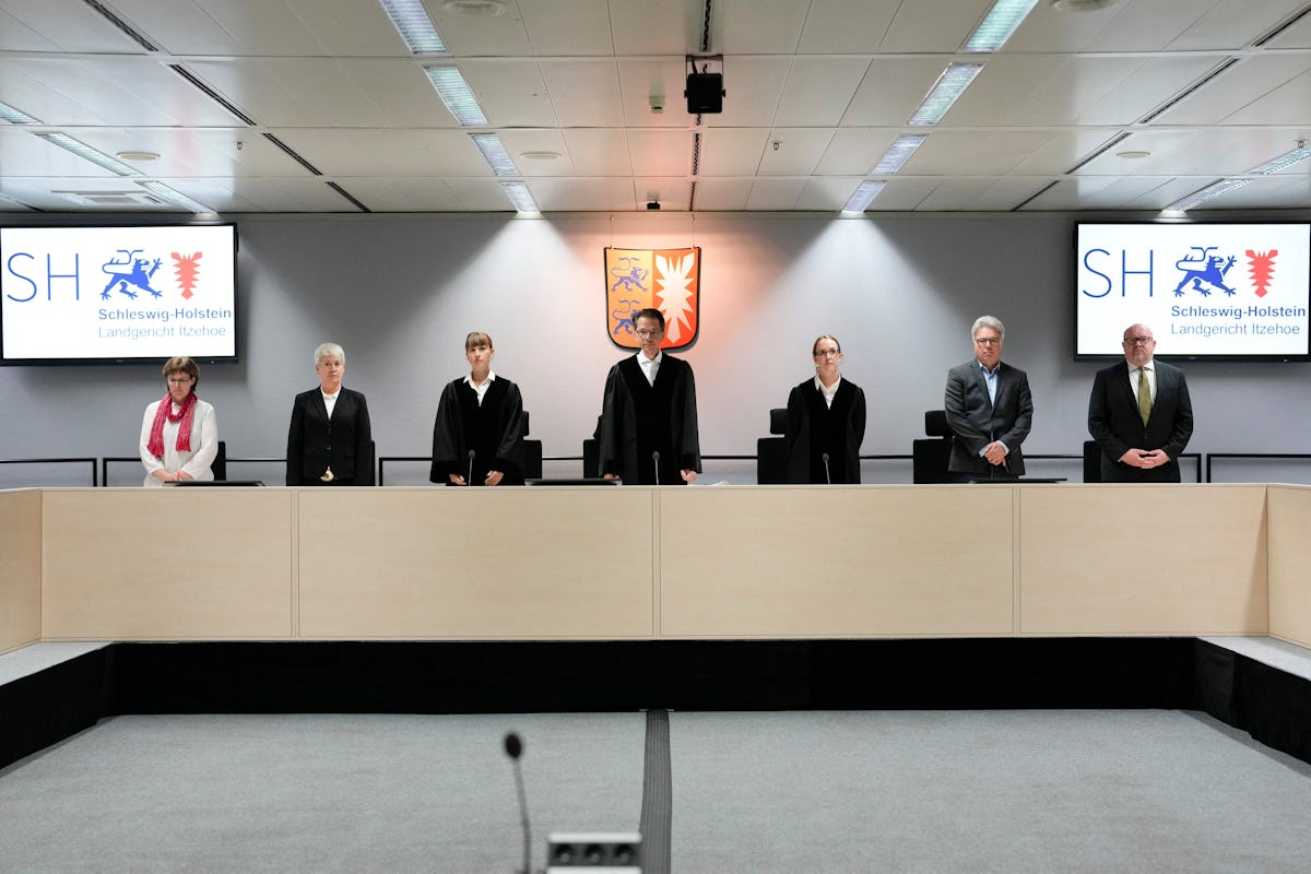 Presiding judge Dominik Gross (C) and the judges pose for the media after arriving for a trial again...