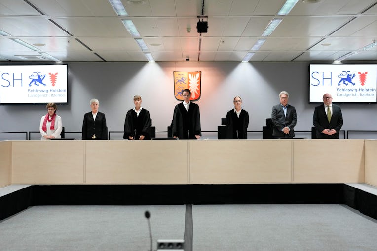 Presiding judge Dominik Gross (C) and the judges pose for the media after arriving for a trial again...