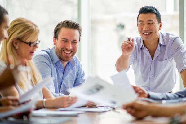 A multi-ethnic group of business professionals are working together in the boardroom.