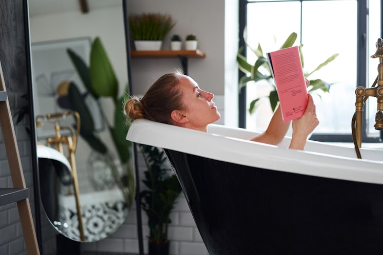 young woman reading a book while taking bath
